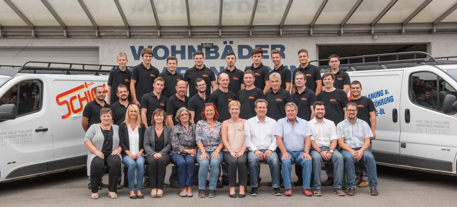 Das Schick-Team vor der Halle mit der Aufschrift Wohnbäder, links und rechts Firmenbusse