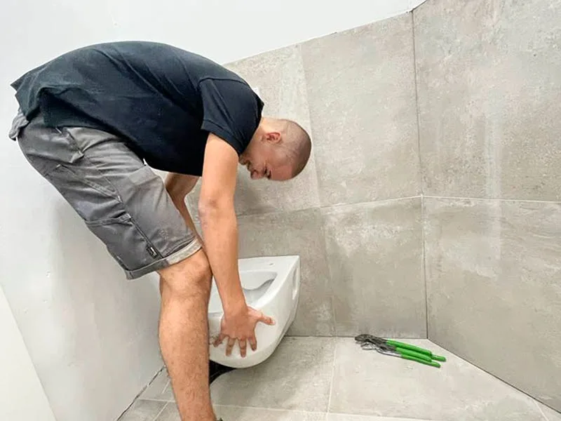 Monteur setzt ein Hänge-WC in einem frisch gefliesten Bad