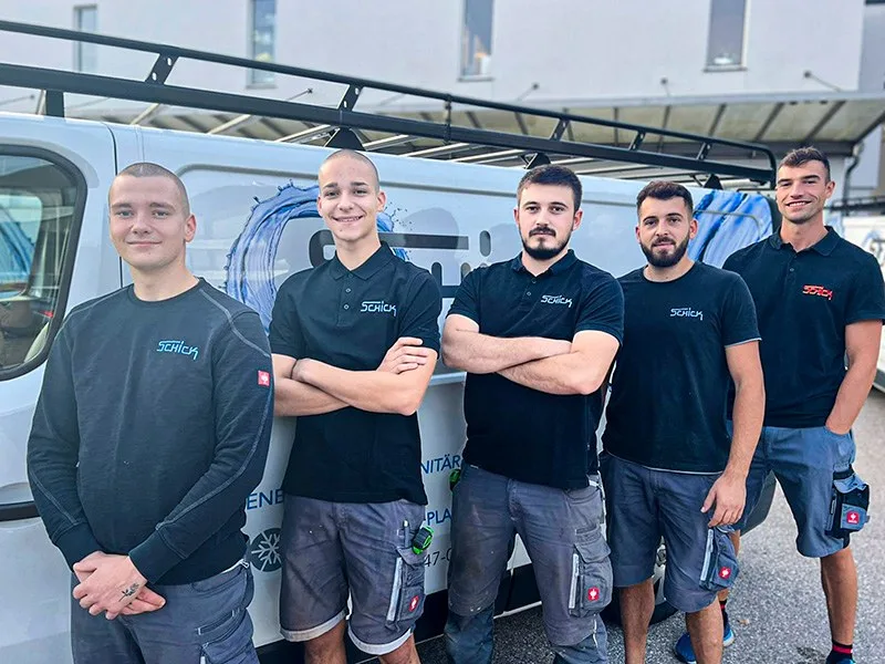 Fünf Monteure in Schick-Shirts vor einem Firmenbus